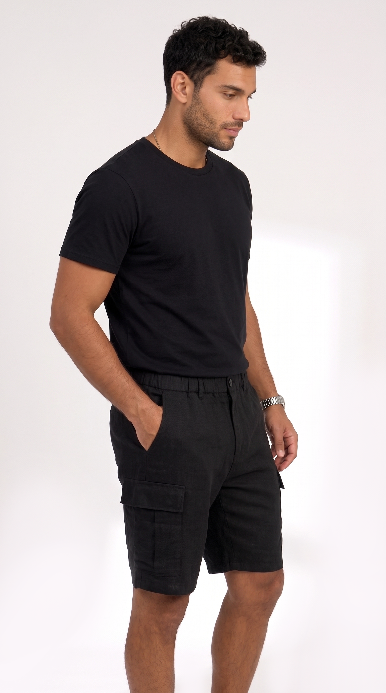A man wearing a black short-sleeve crewneck t-shirt and black cargo shorts, standing against a plain white studio background, from Meleche Fashion USA or Meléche (short as (Mé))