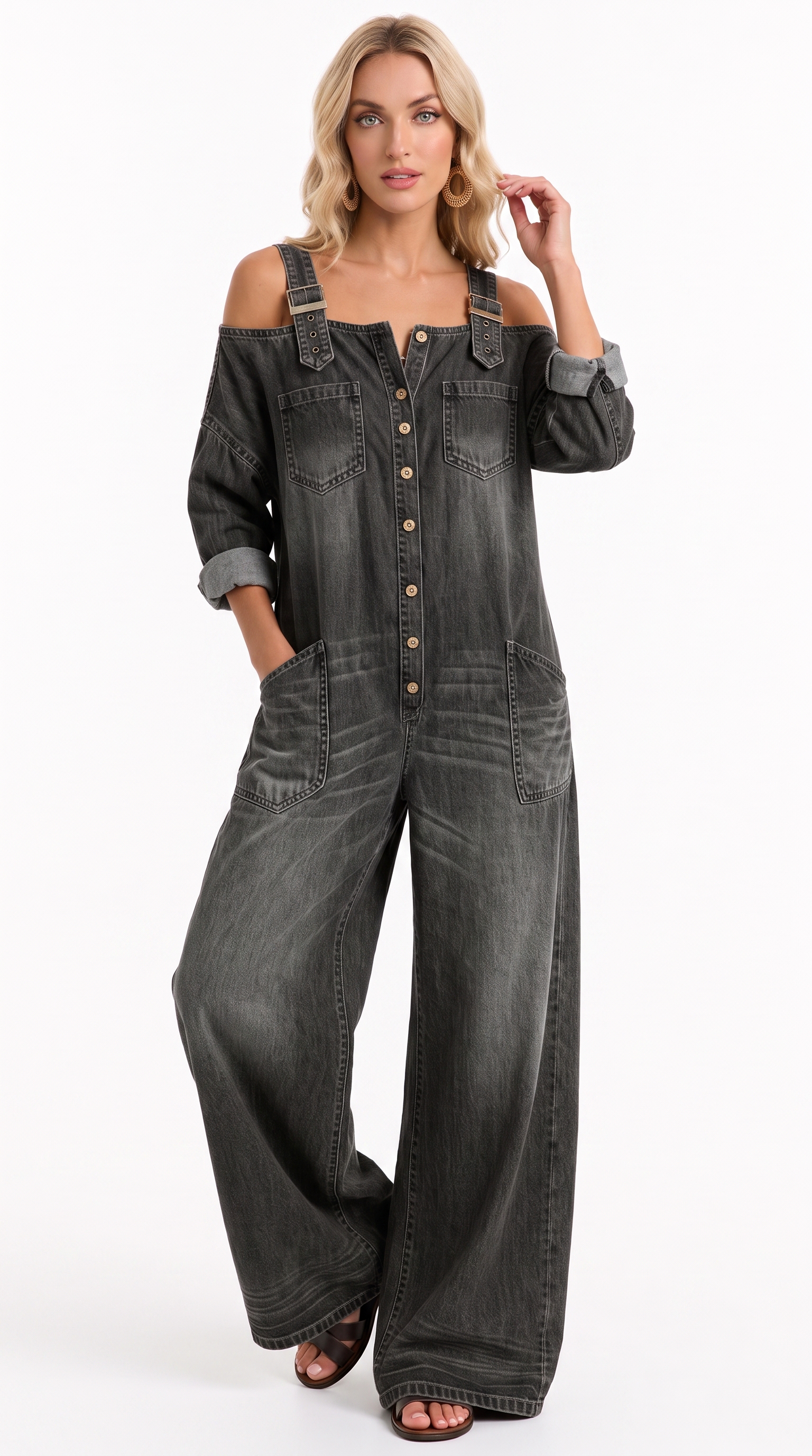 A woman modeling a dark gray washed denim overall jumpsuit with shoulder cutouts, button-front closure, and wide legs, photographed against a plain white studio background, from Meleche Fashion USA or Meléche (short as (Mé))