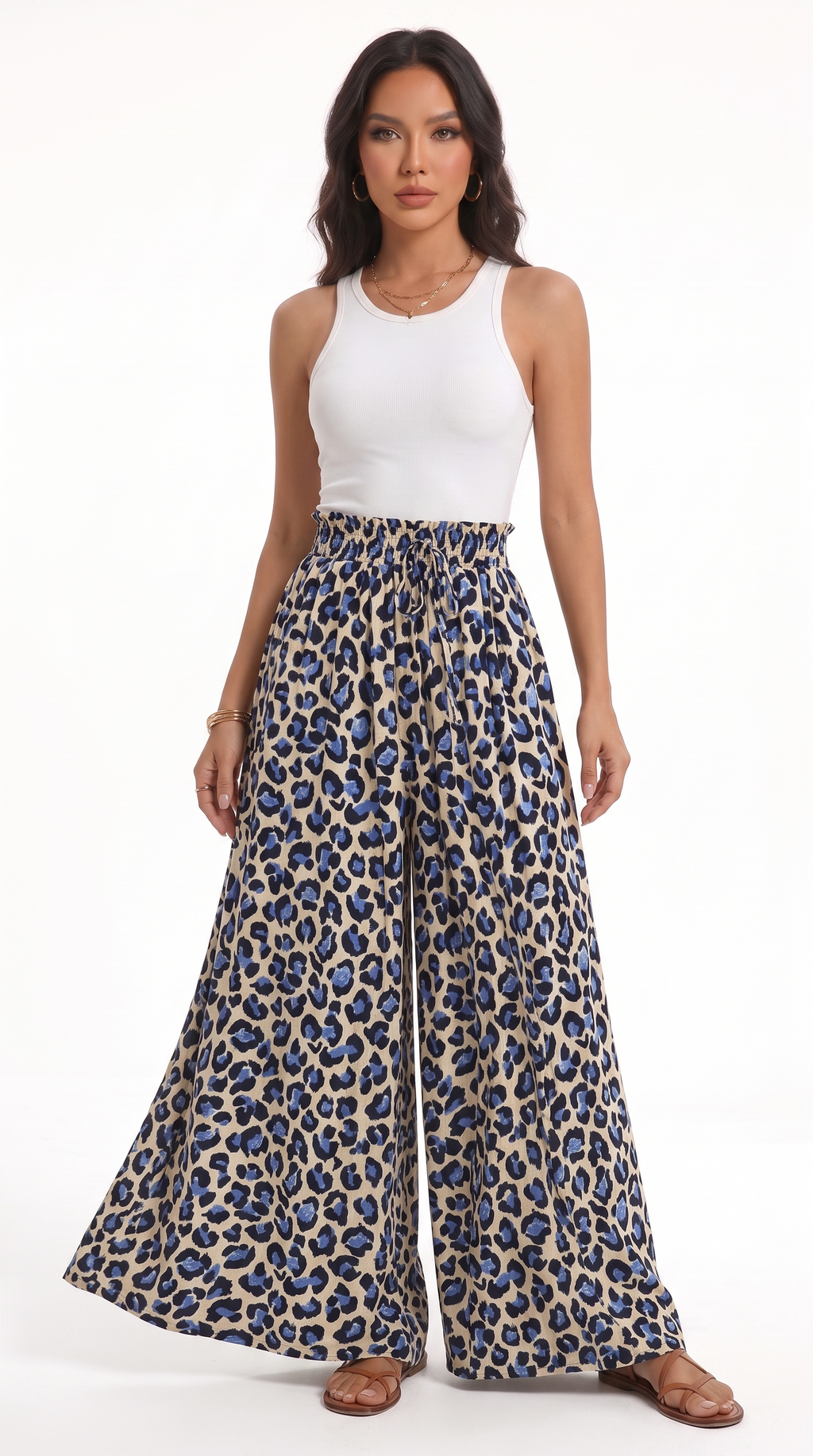 A woman modeling a pair of high-waisted, wide-leg pants with a blue and beige leopard print, paired with a white sleeveless top, against a plain white background, from Meleche Fashion USA or Meléche (short as (Mé))