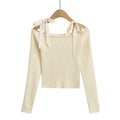 Beige ribbed sweater with bow details on a hanger from Meleche or Meléche (short as (Mé))