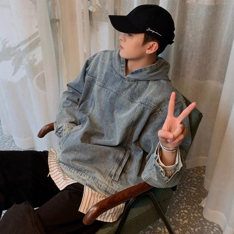 Person wearing a denim jacket and black cap sitting on a chair indoors.