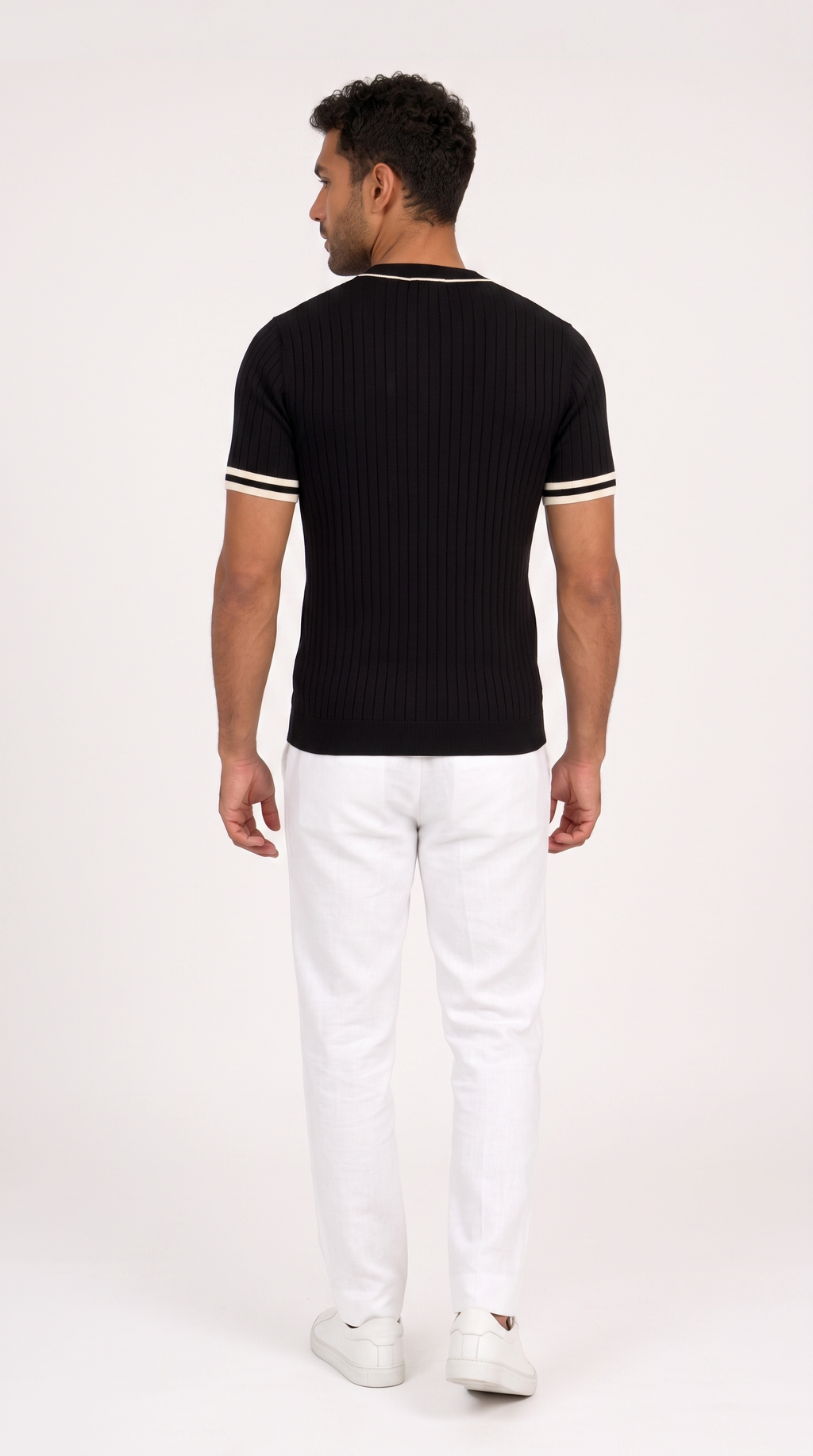A man shown from the back wearing a black ribbed short-sleeve t-shirt with white stripes on the collar and sleeve cuffs, paired with white pants and white sneakers, against a plain white studio background, from Meleche Fashion USA or Meléche (short as (Mé))