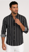 A man wearing a black long-sleeve button-down shirt with vertical white stripes and white pants, standing against a light gray studio background, from Meleche Fashion USA or Meléche (short as (Mé))
