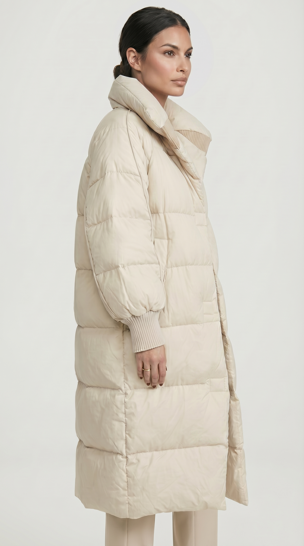 Woman wearing a long beige puffer coat on a white background from Meleche USA or Meléche (short as (Mé))