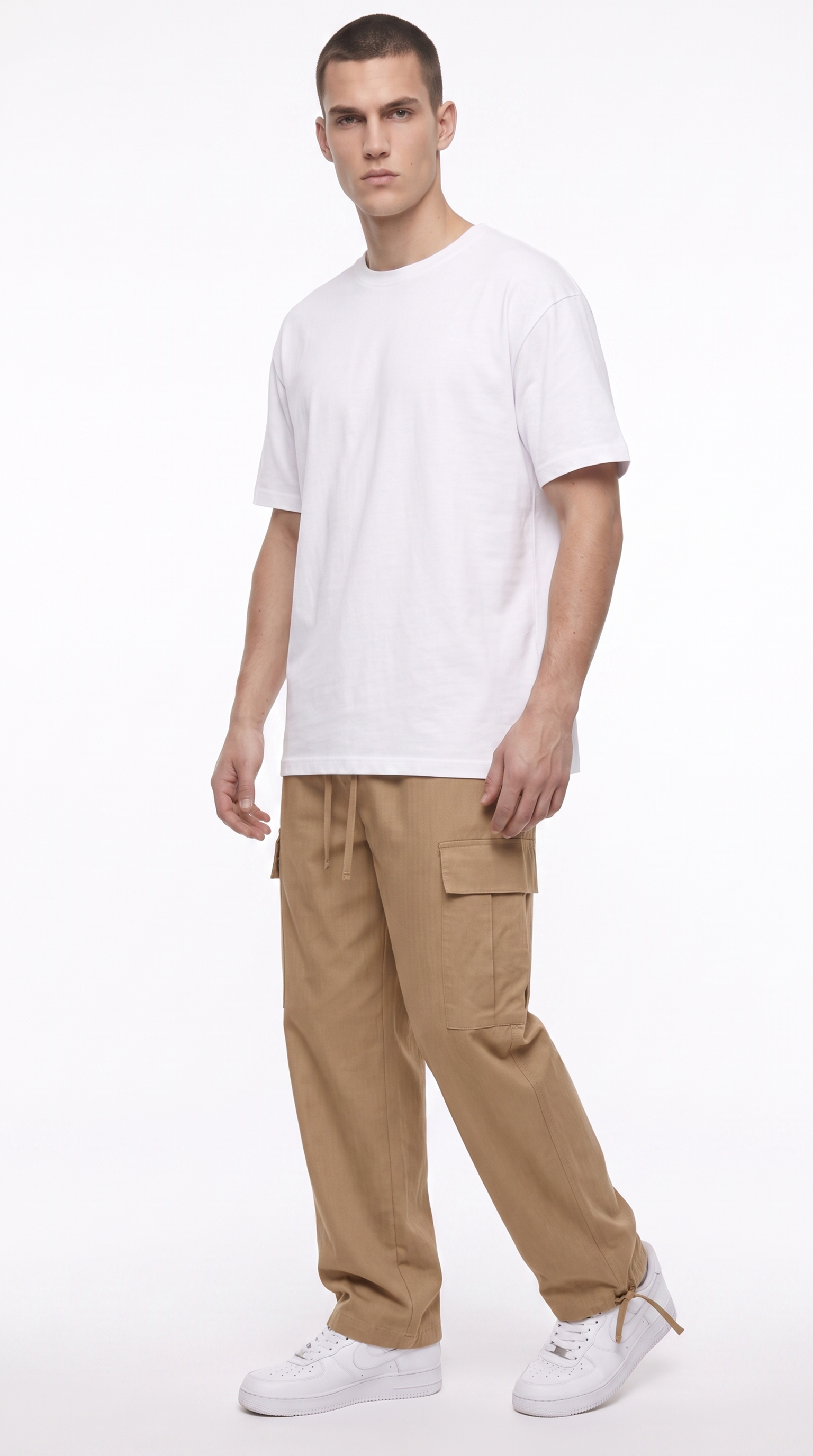 A man modeling a white crew-neck t-shirt and tan cargo pants with white sneakers, standing against a plain white studio background, from Meleche Fashion USA or Meléche (short as (Mé))