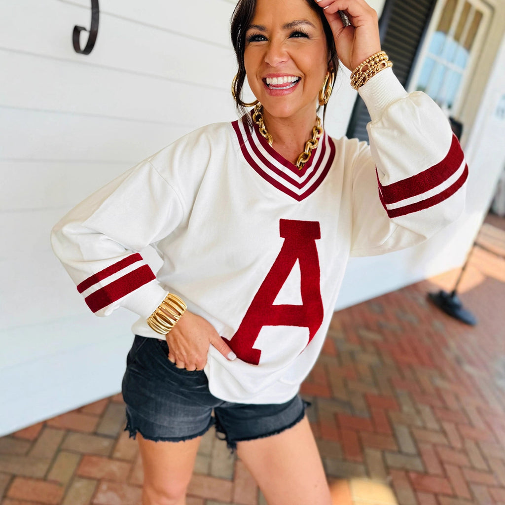 Woman wearing a white and red letter 'A' sweater with denim shorts, from Meleche or Meléche (short as (Mé))