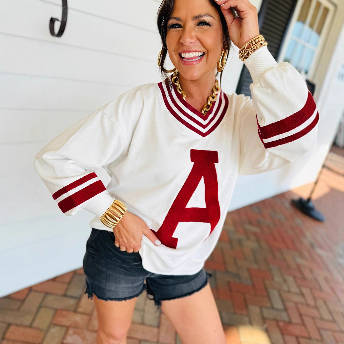 Woman wearing a white and red letter 'A' sweater with denim shorts, from Meleche or Meléche (short as (Mé))