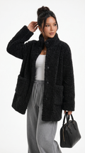 Woman wearing a black sherpa jacket with a white top and gray pants, holding a black handbag on a white background from Meleche Fashion USA or Meléche (short as (Mé))
