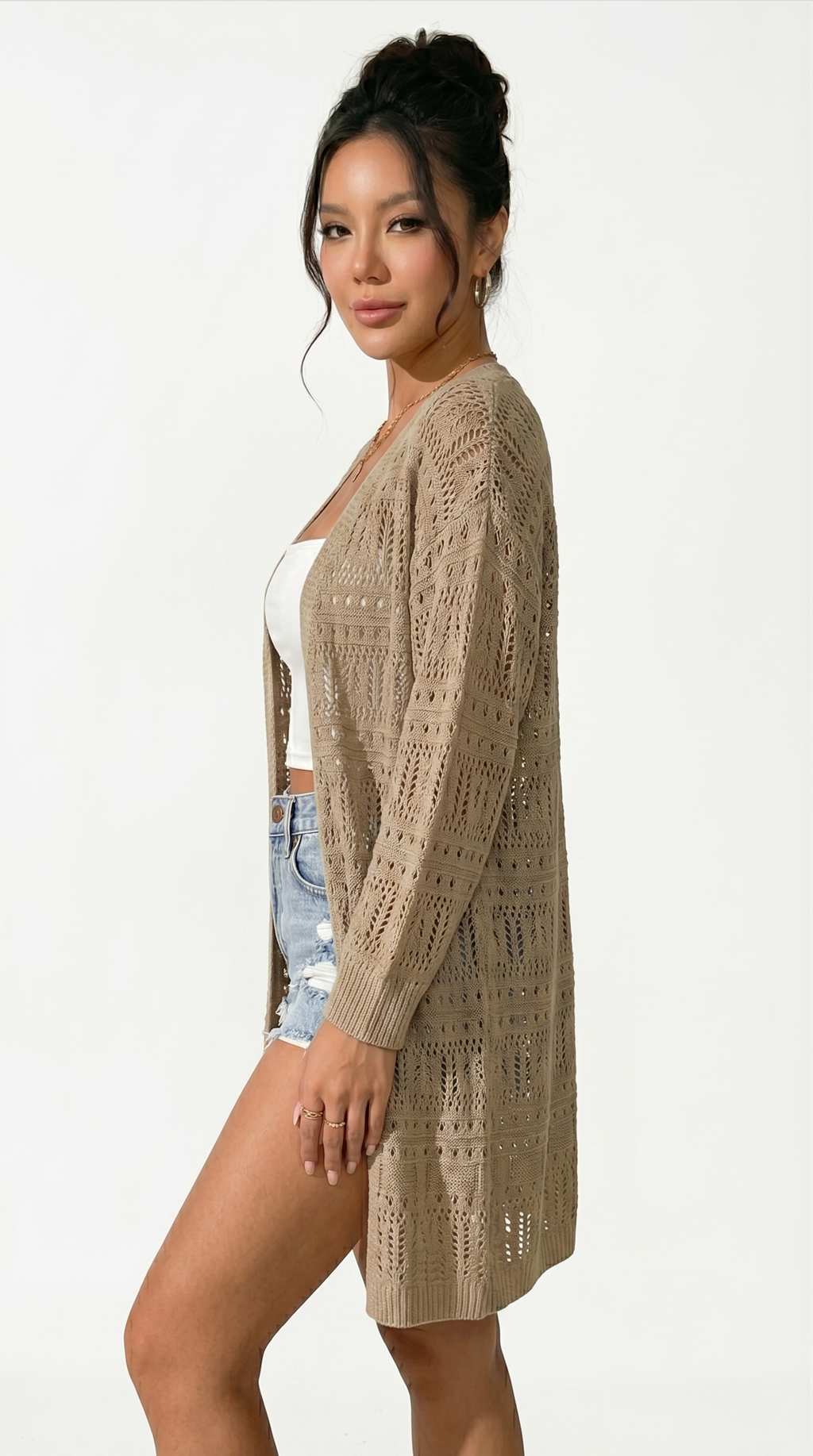 Woman wearing a beige cardigan over a white top and denim shorts on a white background from Meleche or Meléche (short as (Mé))