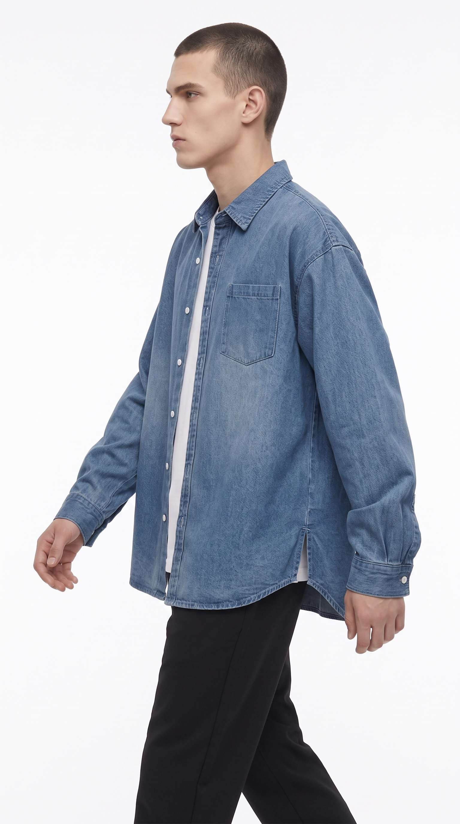 A man wearing a light blue denim button-up shirt over a white undershirt and black trousers, shown in profile against a plain white studio background, from Meleche Fashion USA or Meléche (short as (Mé))