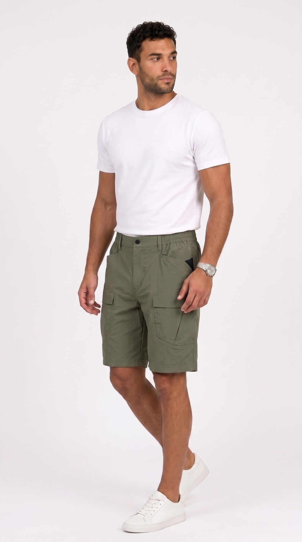 A man wearing olive green cargo shorts, a white t-shirt, and white sneakers, standing against a plain white studio background, from Meleche Fashion USA or Meléche (short as (Mé))