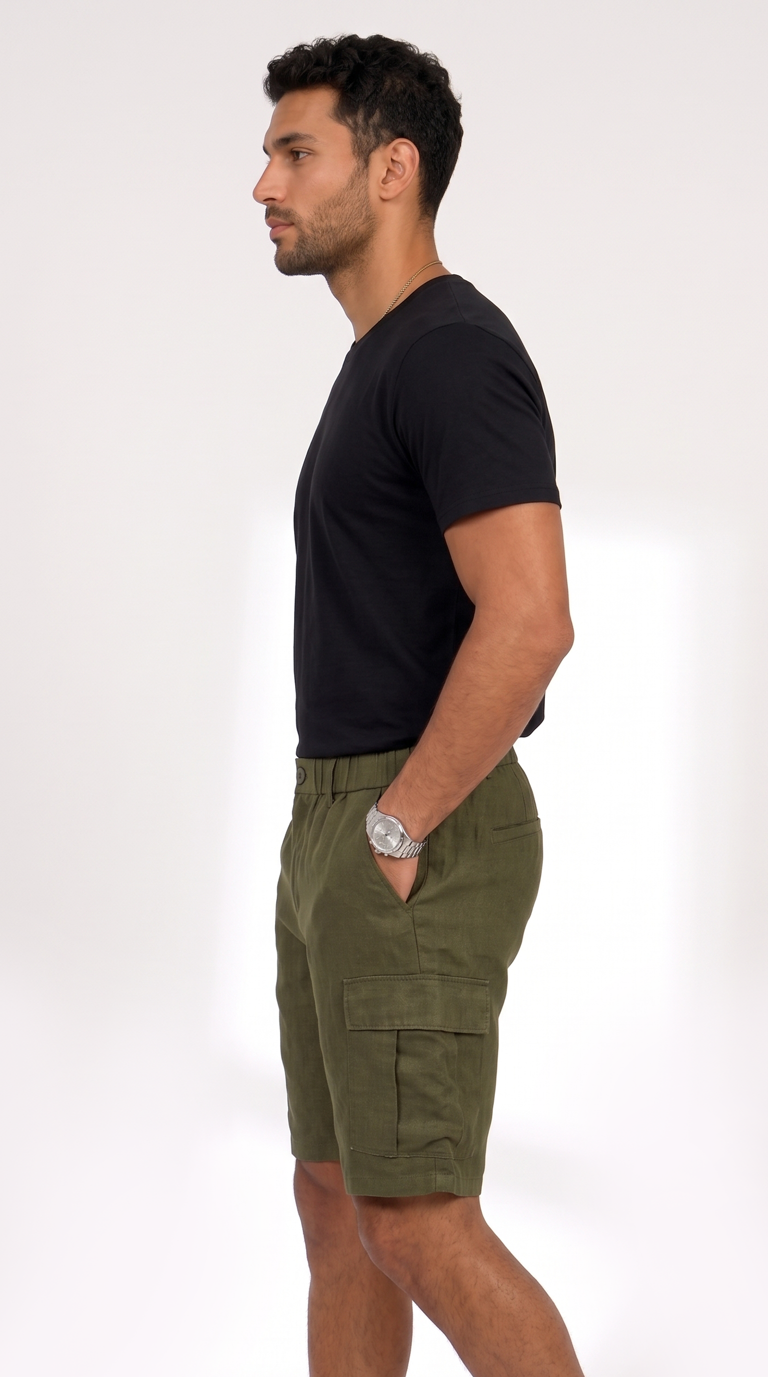 A man in profile wearing a black short-sleeve t-shirt and olive green cargo shorts, standing against a plain white studio background, from Meleche Fashion USA or Meléche (short as (Mé))