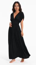 A woman modeling a black maxi dress with a deep V-neckline, short puff sleeves, and a gathered waist, shown against a plain white studio background, from Meleche Fashion USA or Meléche (short as (Mé))