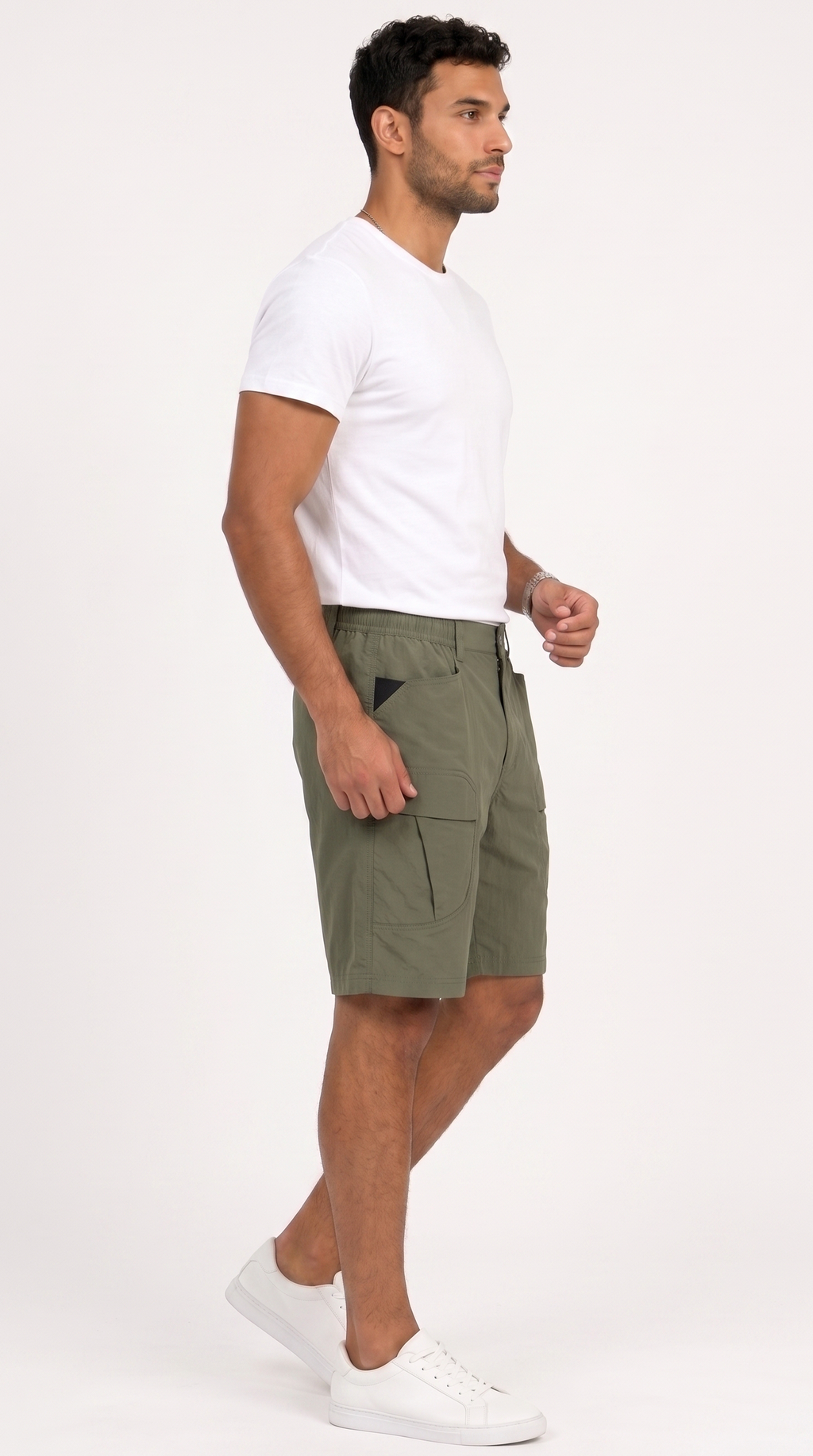 A man wearing olive green cargo shorts, a white t-shirt, and white sneakers, shown in profile against a plain white studio background, from Meleche Fashion USA or Meléche (short as (Mé))