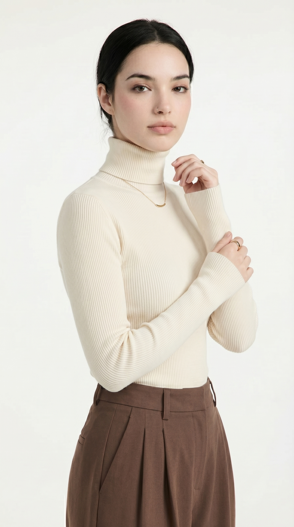 Woman wearing a cream turtleneck sweater and brown pants on a white background from Meleche or Meléche USA (short as (Mé))