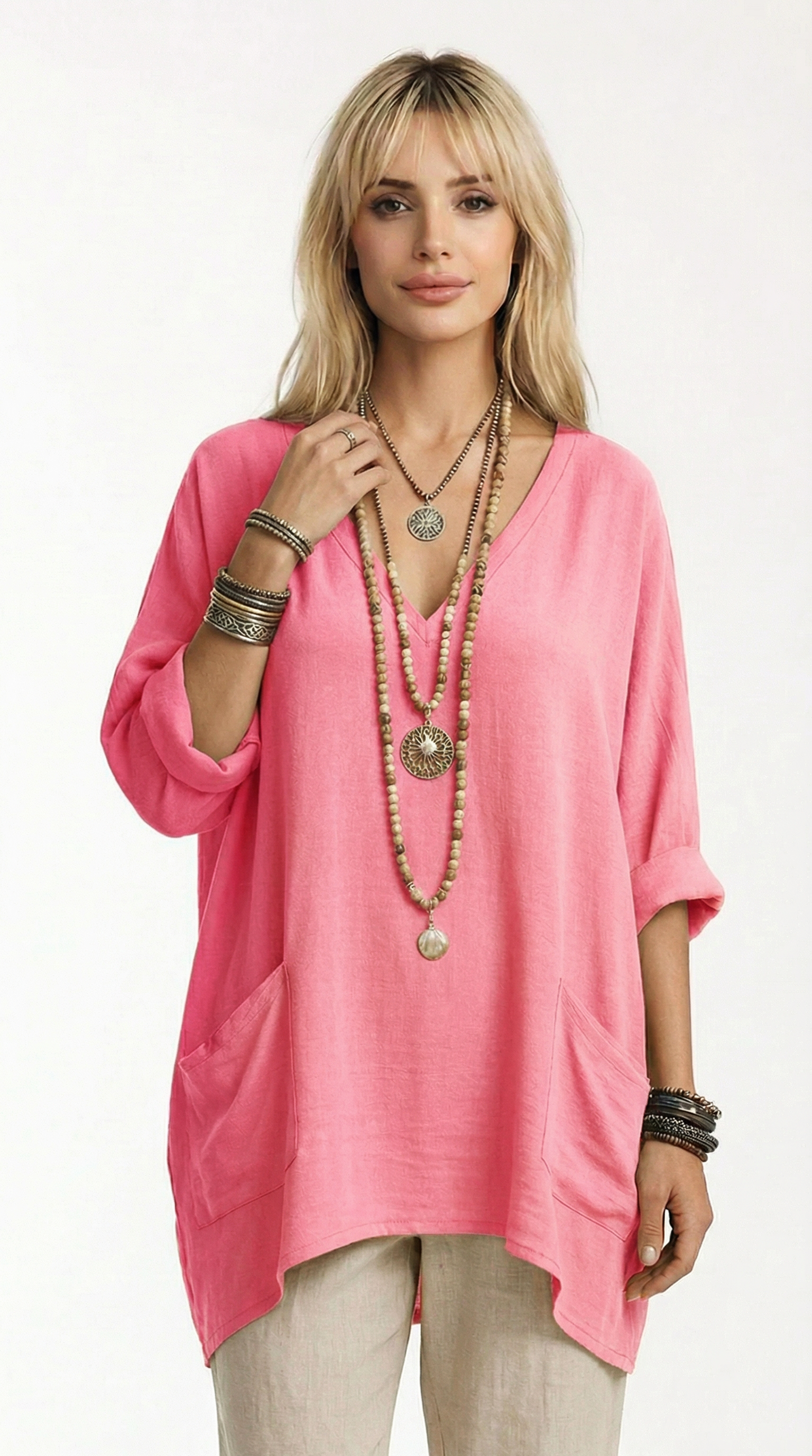 Woman wearing a pink tunic with layered necklaces and bracelets on a white background from Meleche or Meléche (short as (Mé))