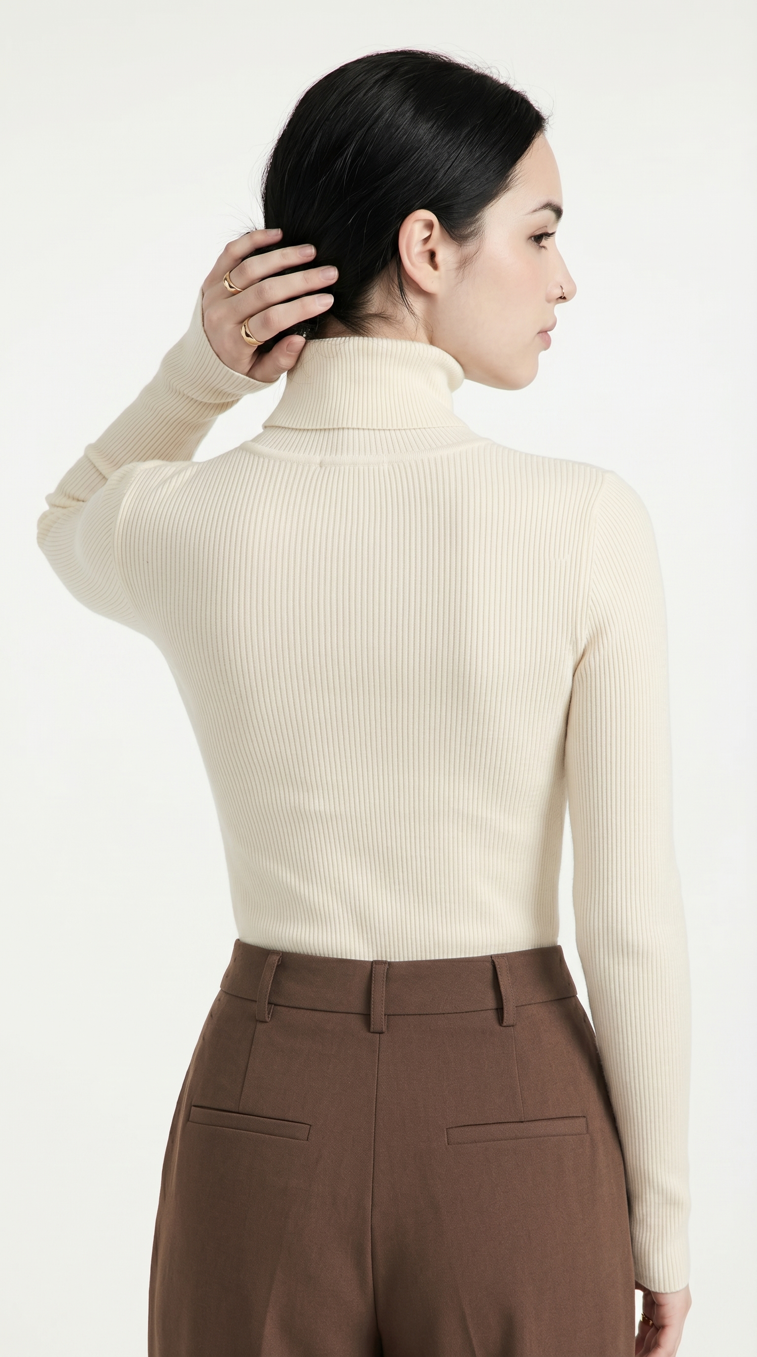 Woman wearing a cream ribbed turtleneck sweater and brown pants on a white background from Meleche or Meléche USA (short as (Mé))