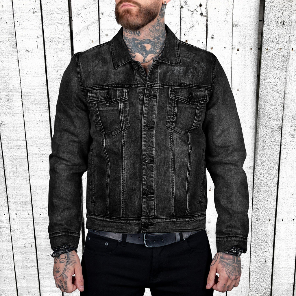 Man wearing a black denim jacket against a wooden panel background
