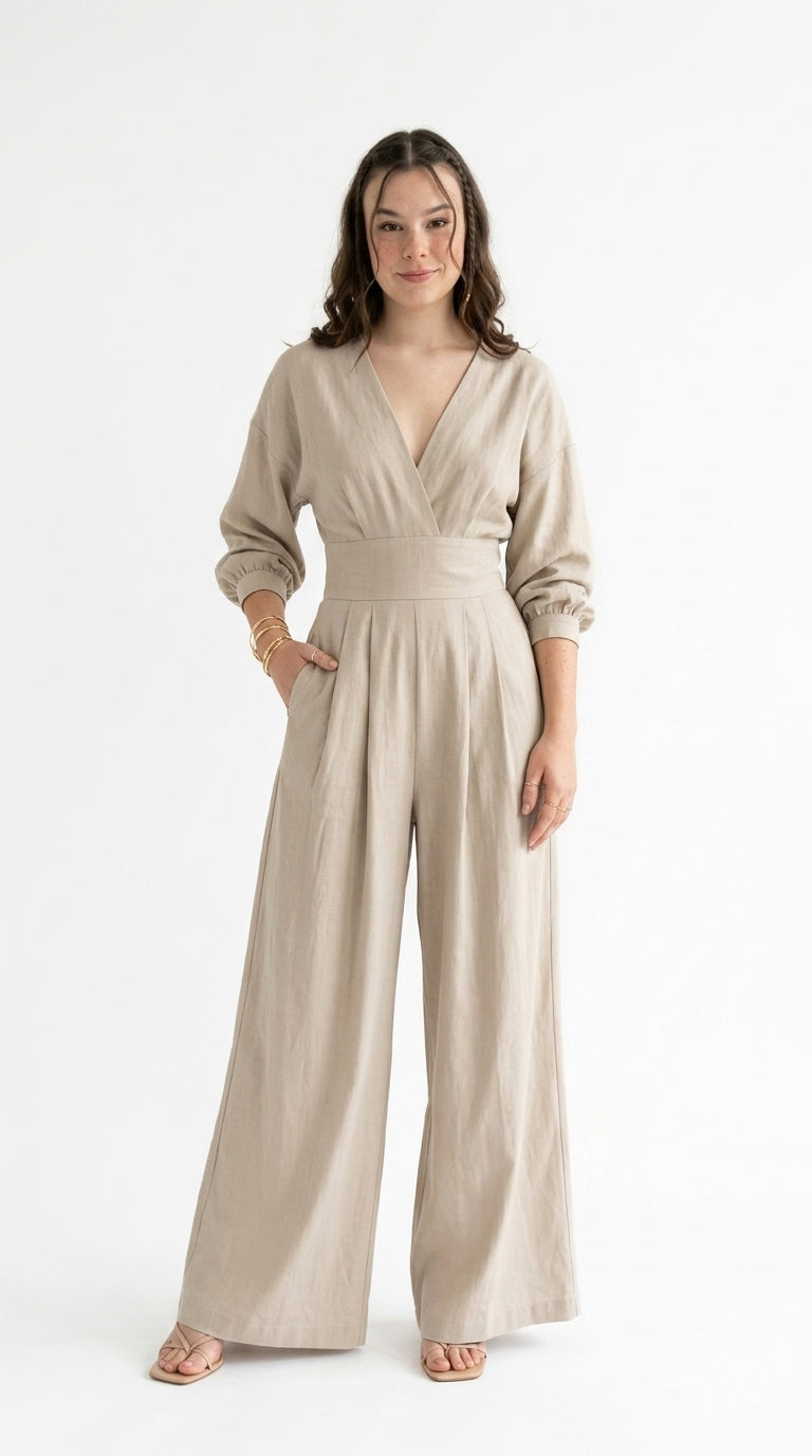 A woman modeling a light beige linen jumpsuit with a wrap-style V-neck bodice, long sleeves with rolled cuffs, and wide legs, standing against a plain white studio background, from Meleche Fashion USA or Meléche (short as (Mé))