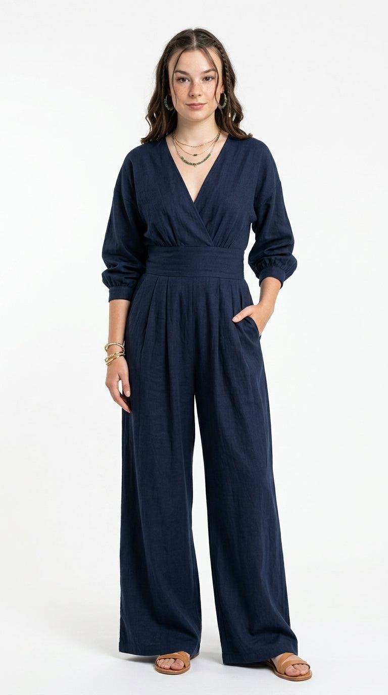 A woman modeling a navy blue wrap-style jumpsuit with three-quarter sleeves and wide legs, standing against a plain white studio background, from Meleche Fashion USA or Meléche (short as (Mé))