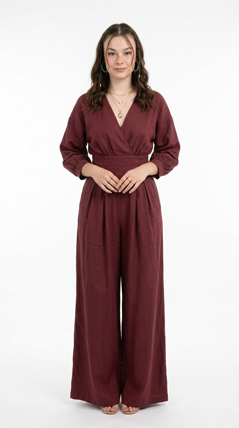 A woman modeling a burgundy wrap-style jumpsuit with three-quarter sleeves and wide legs, standing against a plain white studio background, from Meleche Fashion USA or Meléche (short as (Mé))