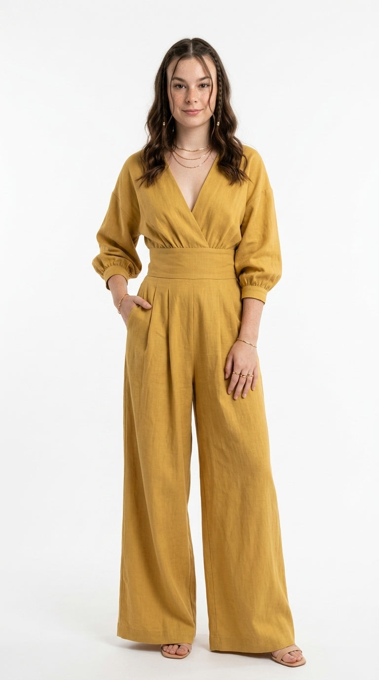 A woman modeling a mustard yellow linen jumpsuit with a wrap-style V-neck bodice, three-quarter sleeves, and wide legs, standing against a plain white studio background, from Meleche Fashion USA or Meléche (short as (Mé))