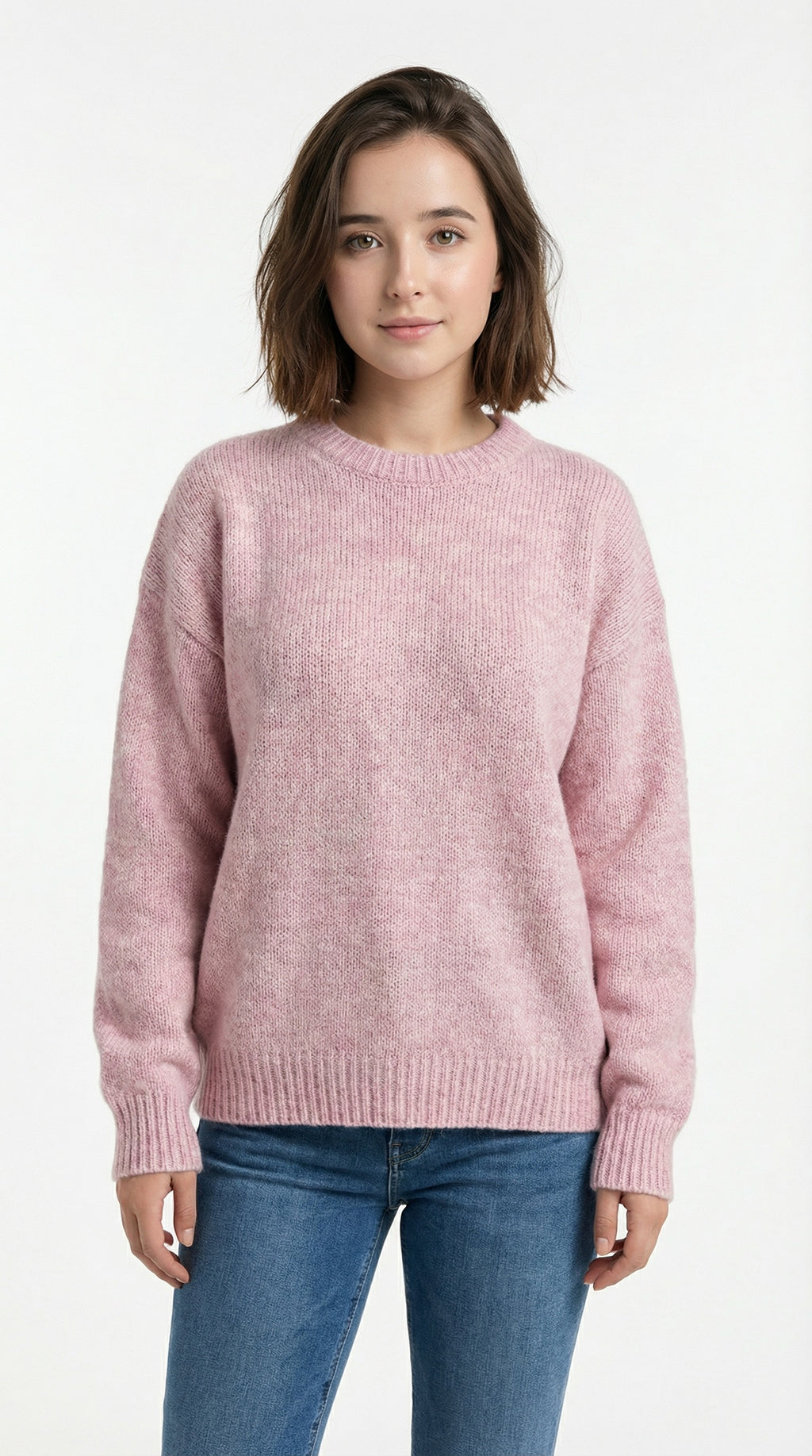 Person wearing a pink sweater and blue jeans standing on a street.