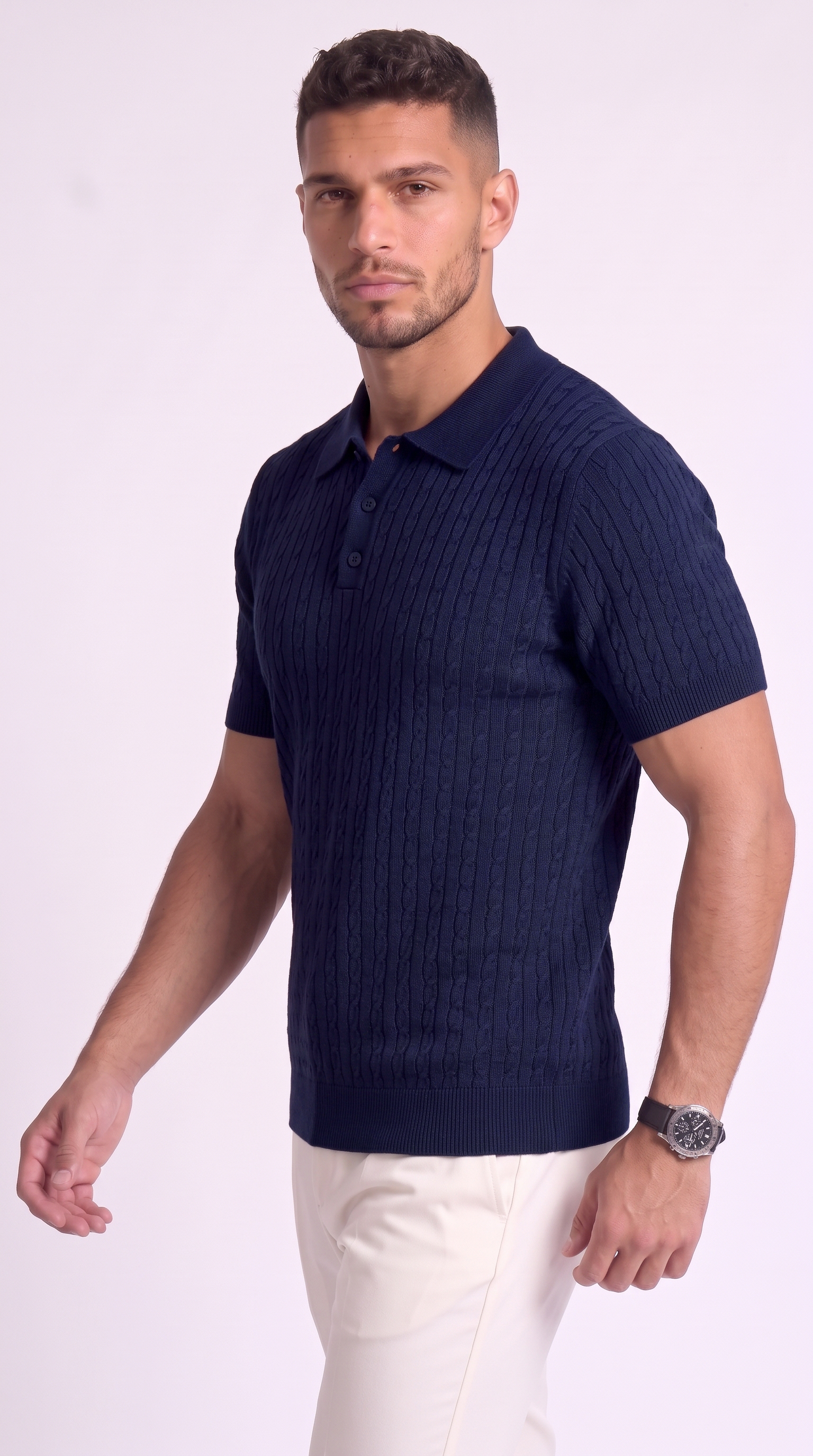 A man wearing a dark navy blue ribbed knit polo shirt and off-white trousers, standing against a light studio background, from Meleche Fashion USA or Meléche (short as (Mé))