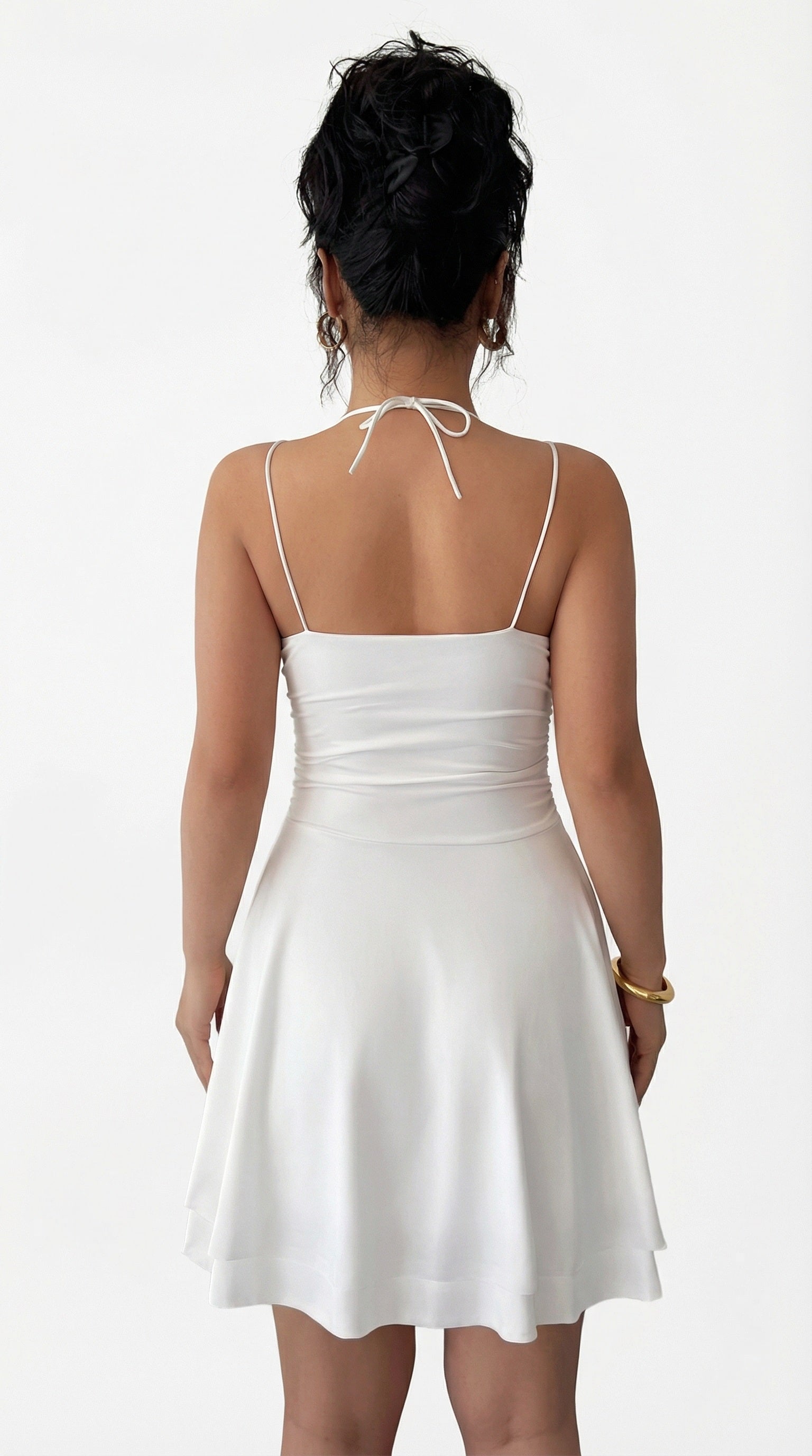 Woman wearing a white dress with thin straps in a minimal indoor setting