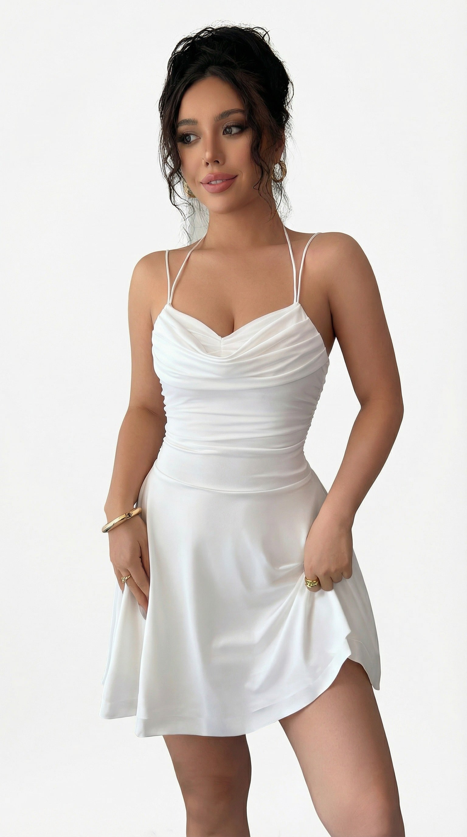 Woman wearing a white dress standing against a neutral background