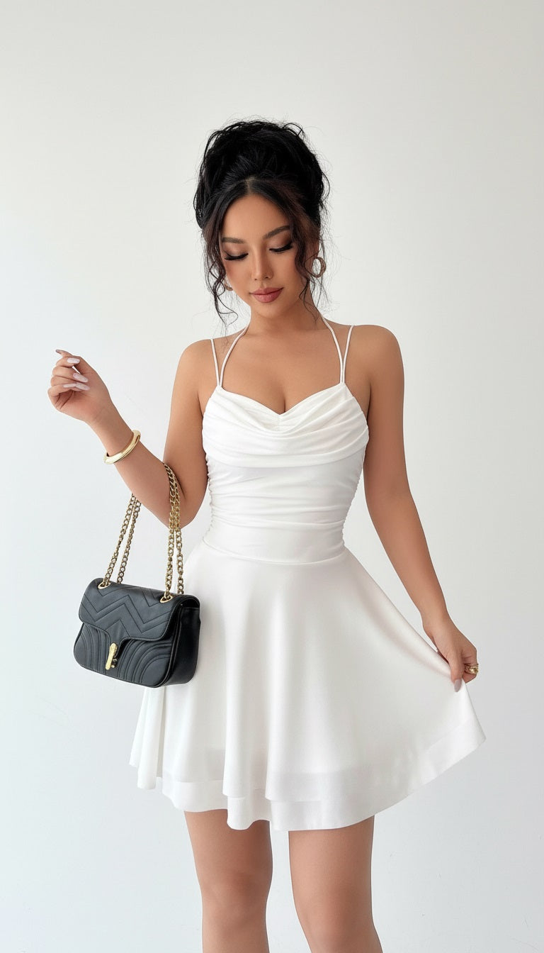 Woman in a white dress holding a black handbag against a neutral background
