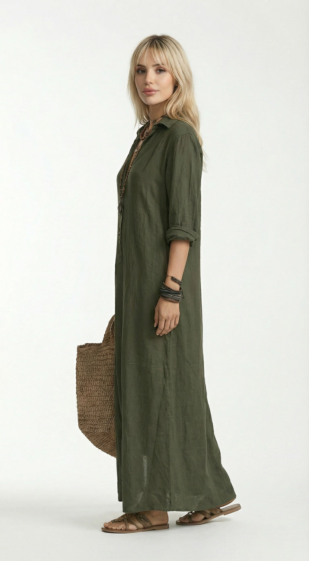 Woman wearing an olive green dress holding a woven bag against a neutral background