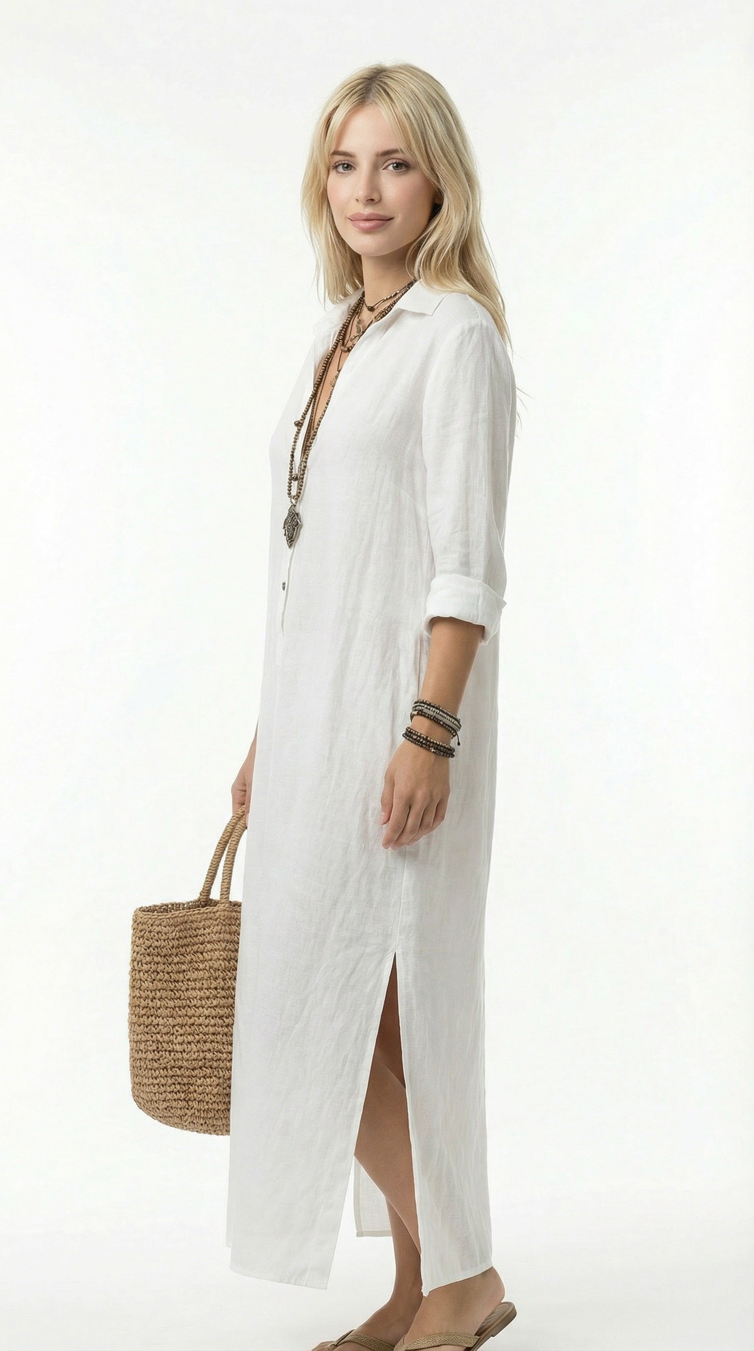 Woman wearing a long white shirt dress holding a woven bag against a neutral background