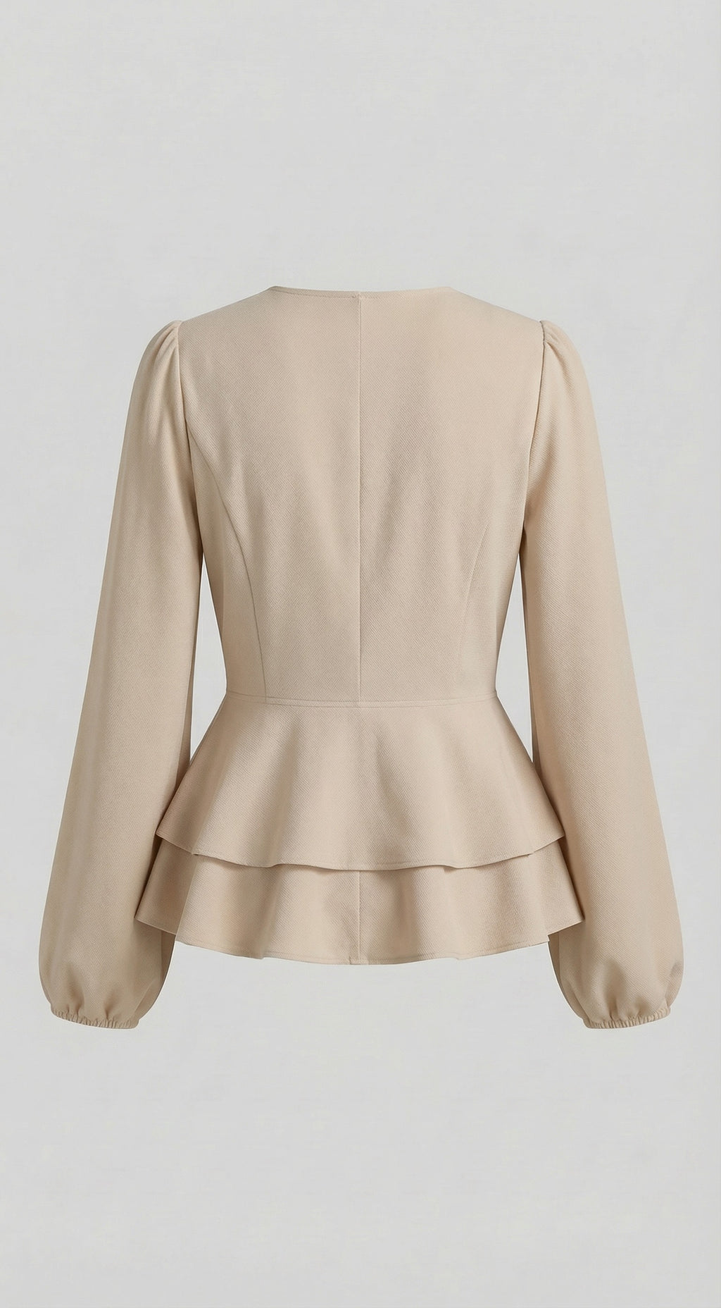 Woman wearing a beige blazer and blue jeans against a neutral background 