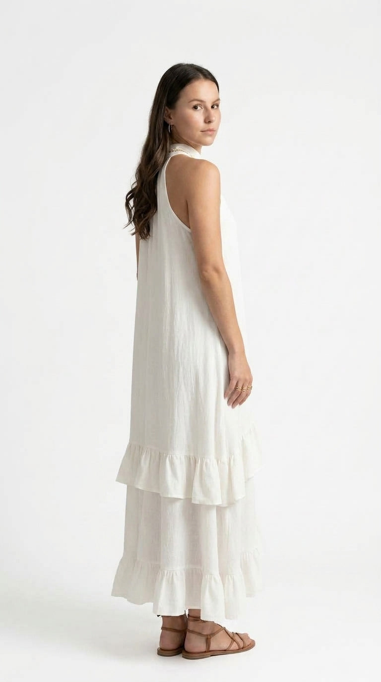 A woman modeling a sleeveless white tiered maxi dress, shown from a side-back angle against a clean white studio background, from Meleche Fashion USA or Meléche (short as (Mé))