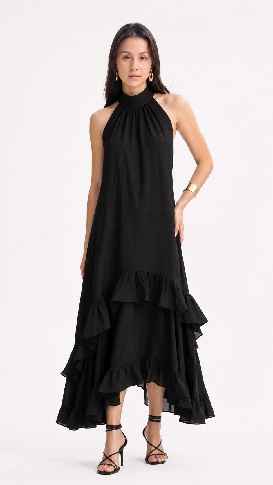 A woman modeling a black halter-neck midi dress with a high-low ruffled hem and black strappy heels against a plain white studio background, from Meleche Fashion USA or Meléche (short as (Mé))