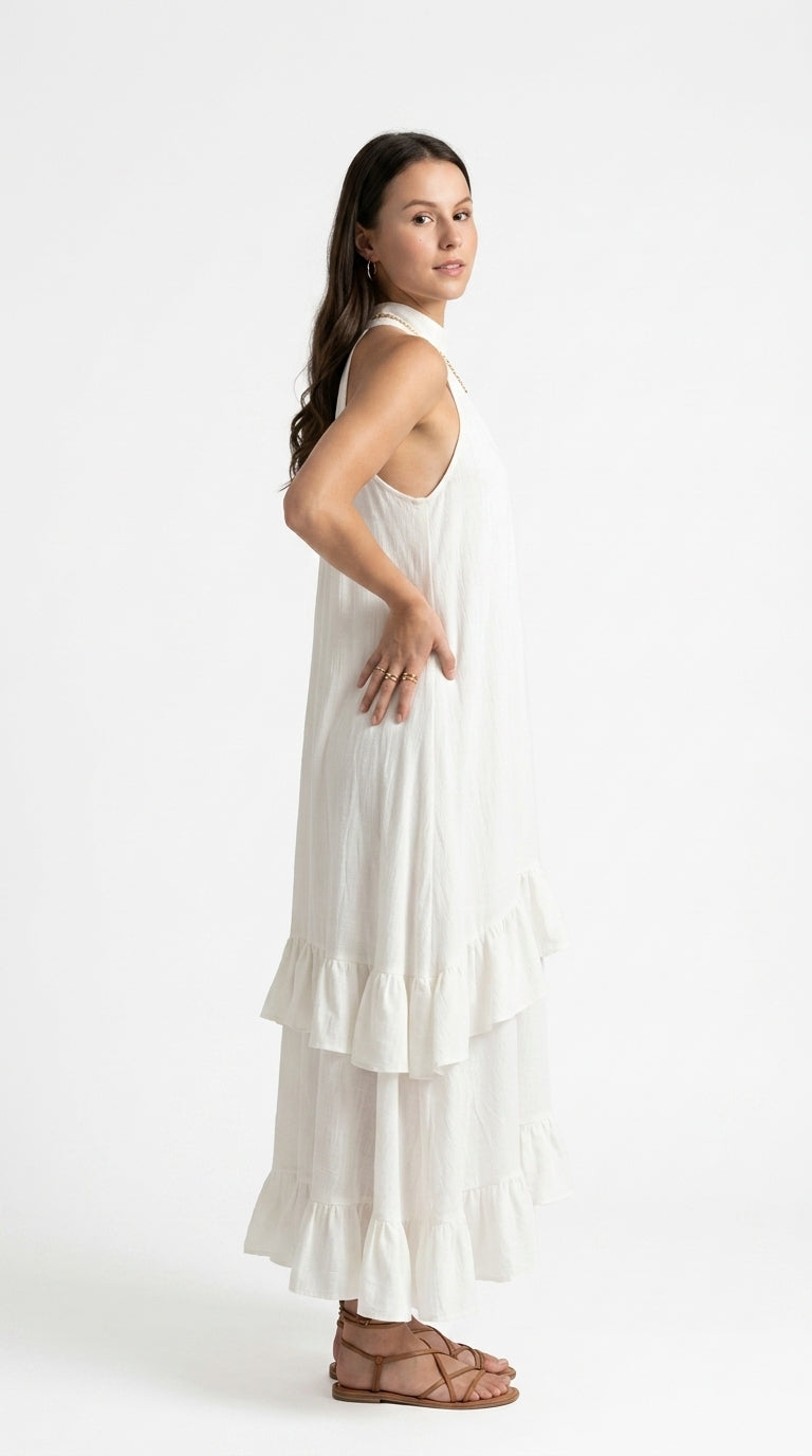 A woman modeling a sleeveless white tiered maxi dress with a high neck, shown from a side-back angle against a plain white studio background, from Meleche Fashion USA or Meléche (short as (Mé))