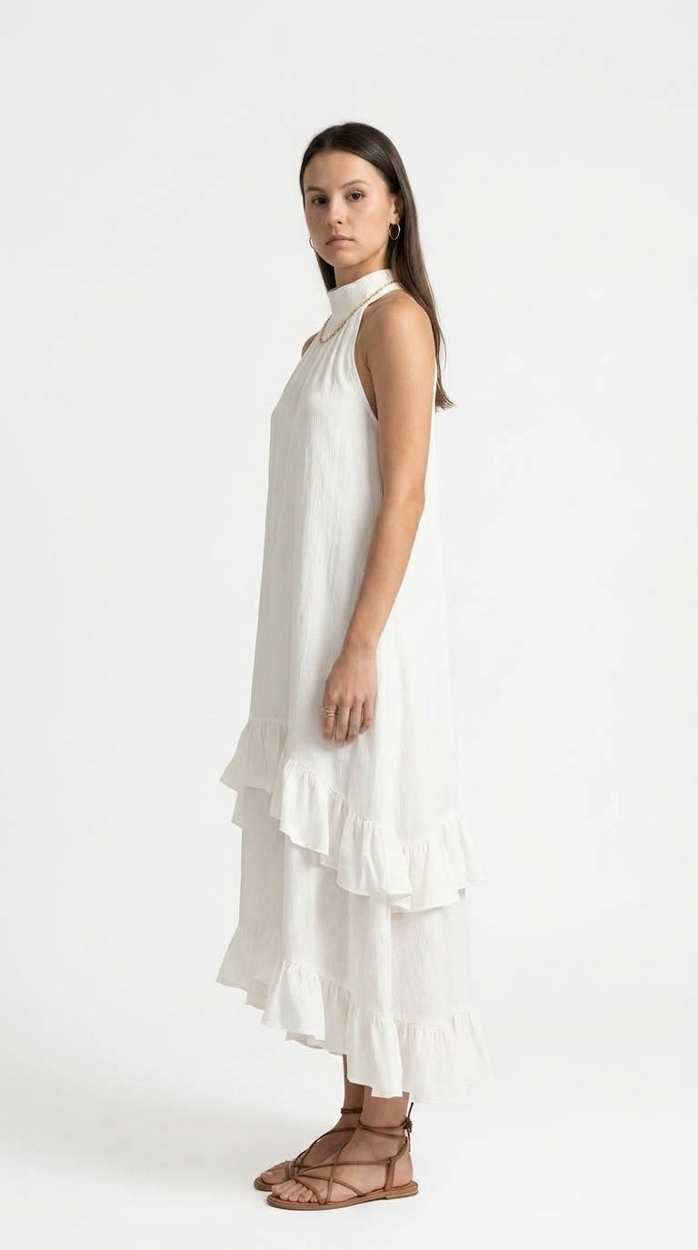 A woman modeling a sleeveless white tiered maxi dress with a high neckline, paired with brown strappy flat sandals, against a plain white studio background, from Meleche Fashion USA or Meléche (short as (Mé))