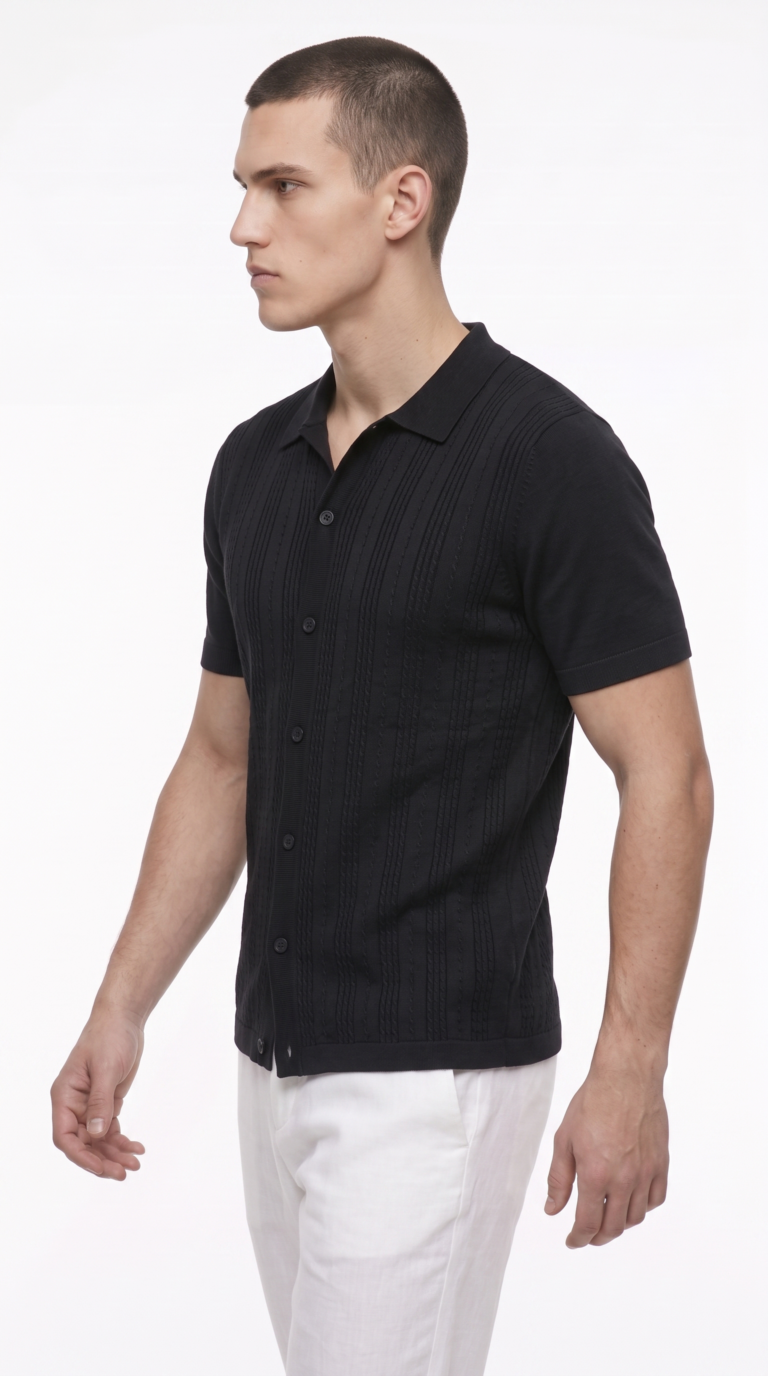 A man wearing a black short-sleeve button-up shirt with a subtle vertical ribbed texture and white trousers, photographed against a plain white studio background, from Meleche Fashion USA or Meléche (short as (Mé))