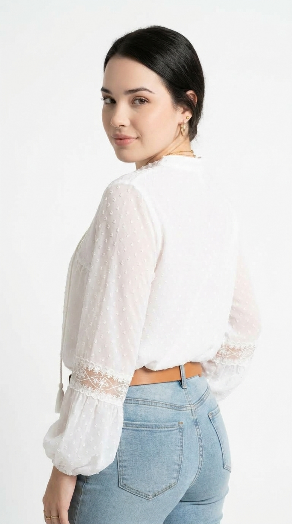 A woman wearing a white long-sleeve blouse with sheer textured fabric and lace cuffs, paired with light blue jeans, photographed against a plain white studio background, from Meleche Fashion USA or Meléche (short as (Mé))