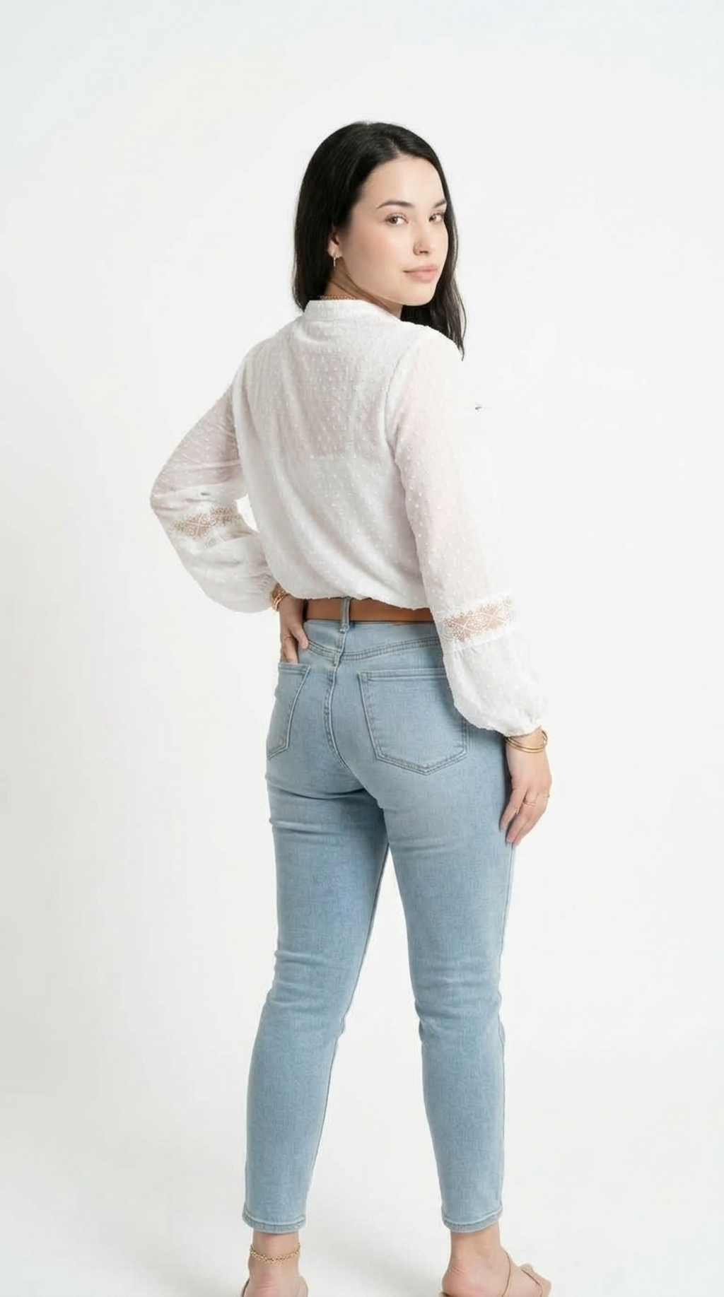 A woman is shown from the back wearing a white textured long-sleeve blouse and light blue skinny jeans, standing against a plain white studio background, from Meleche Fashion USA or Meléche (short as (Mé))