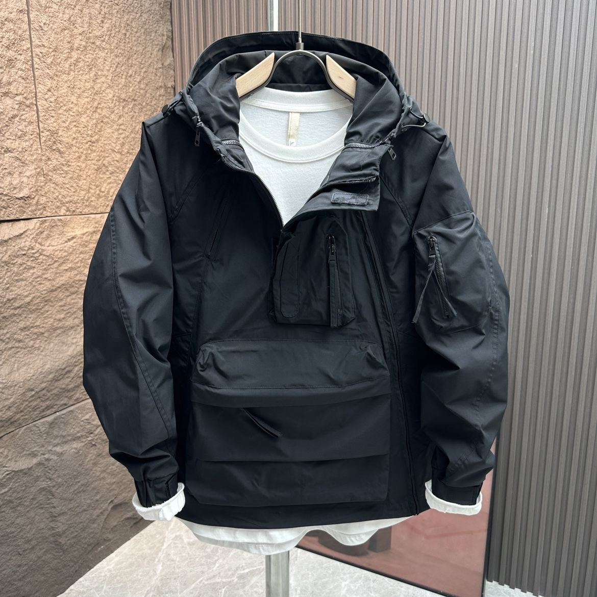 Black jacket on a hanger against a textured wall.