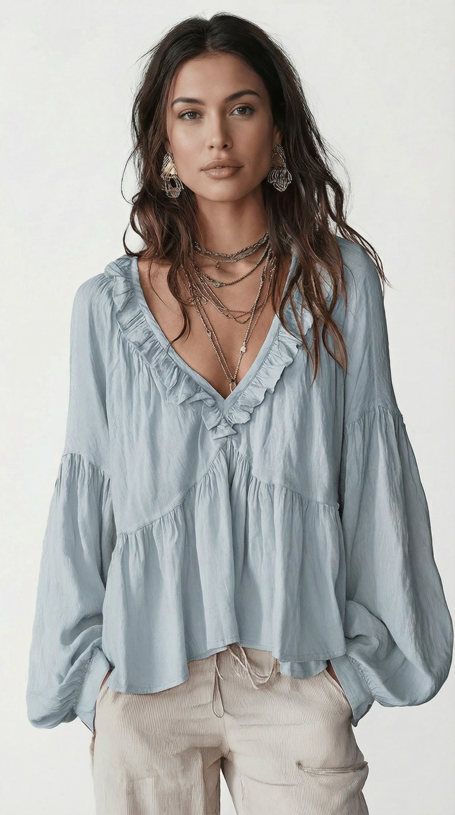 Woman wearing a light blue blouse with ruffled details on a white background