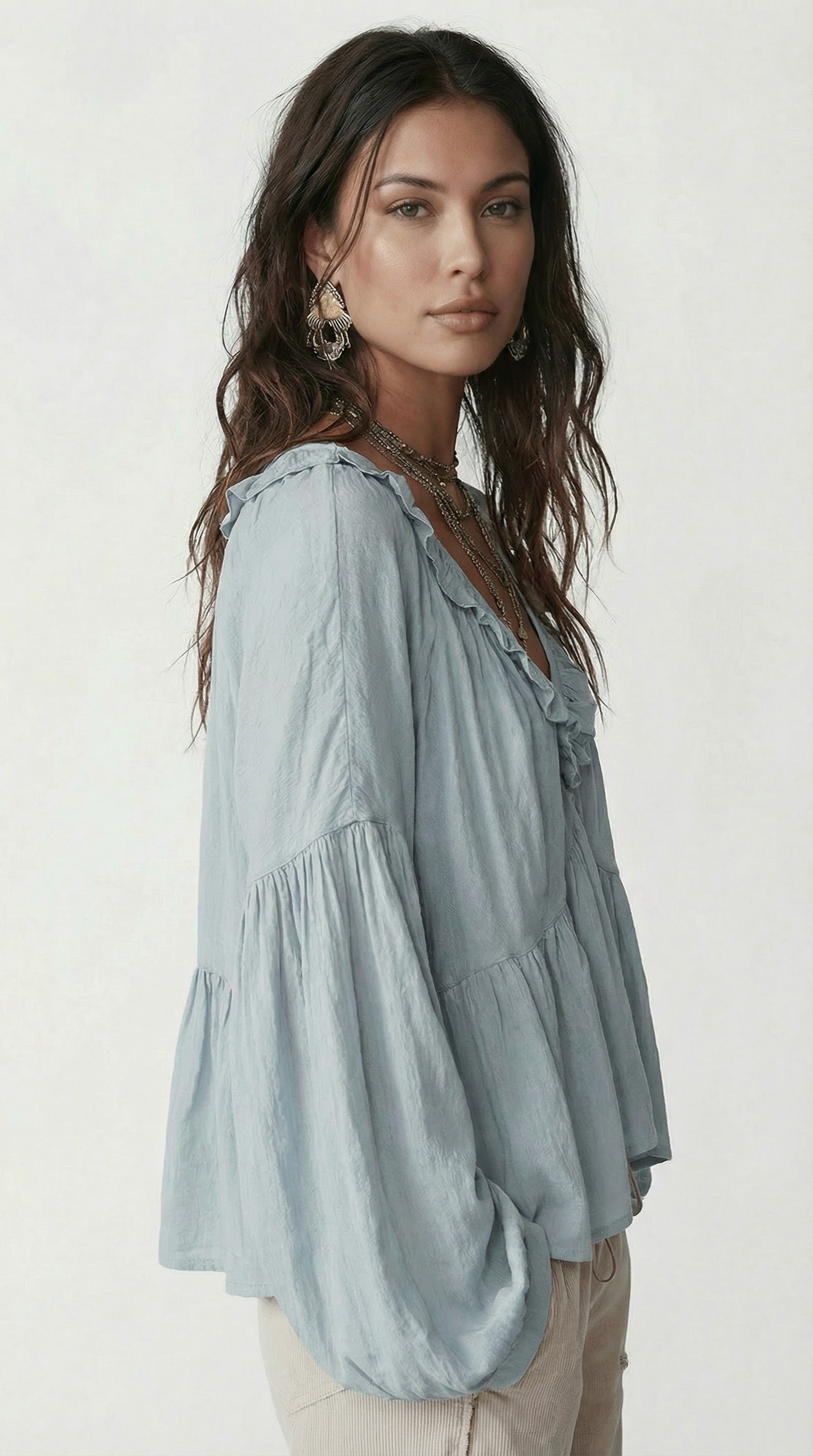 Woman wearing a light blue blouse with ruffled sleeves on a white background from Meleche Fashion USA or Meléche (short as (Mé))