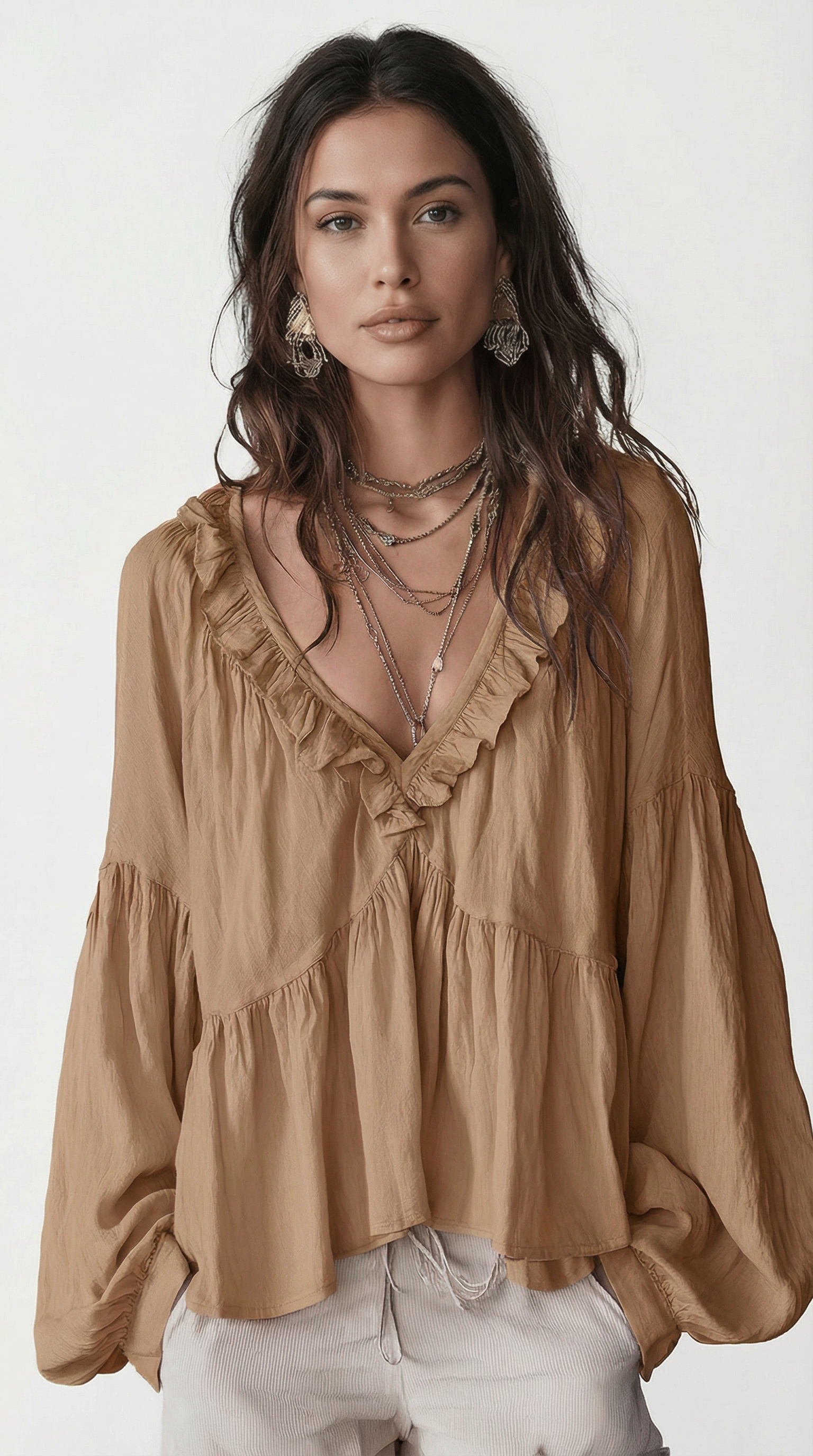 Woman wearing a beige blouse with ruffled details on a white background