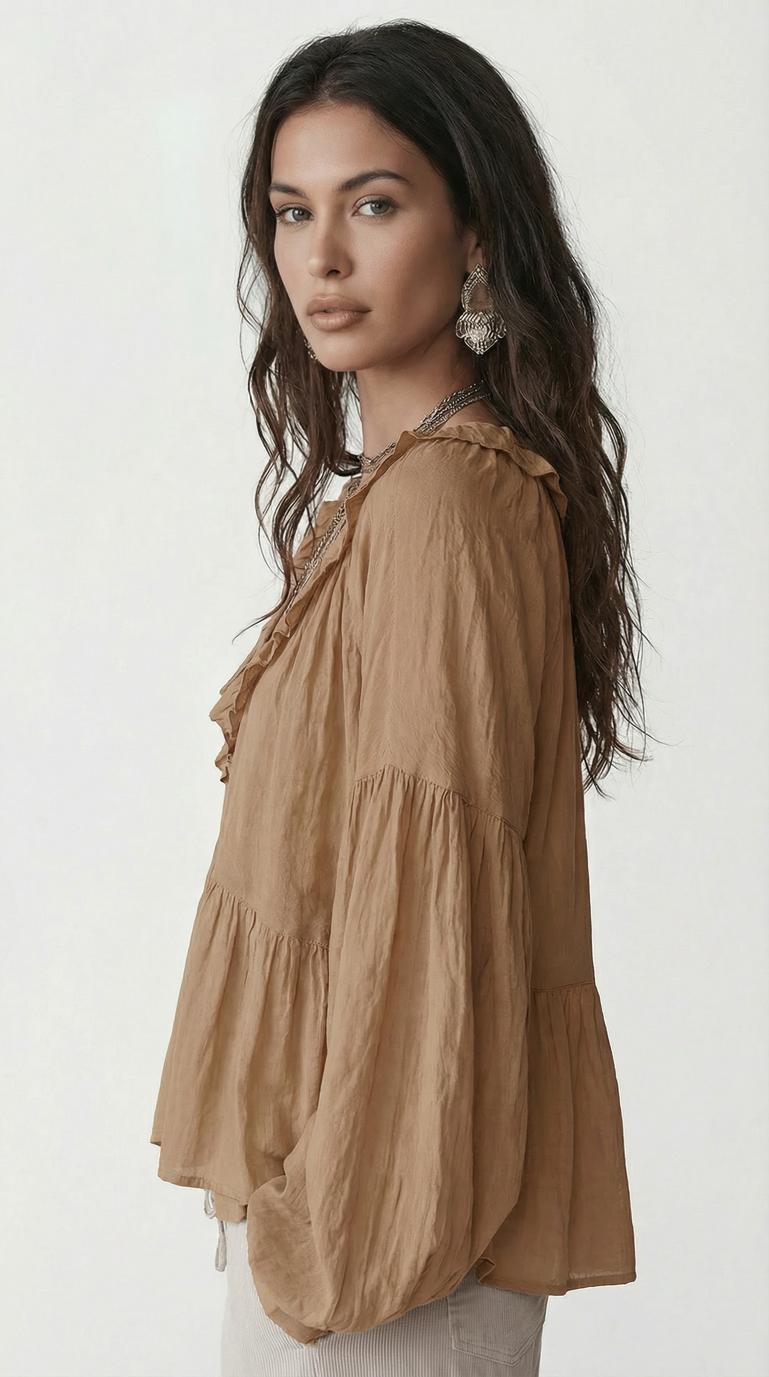 Woman wearing a brown tiered blouse against a white background