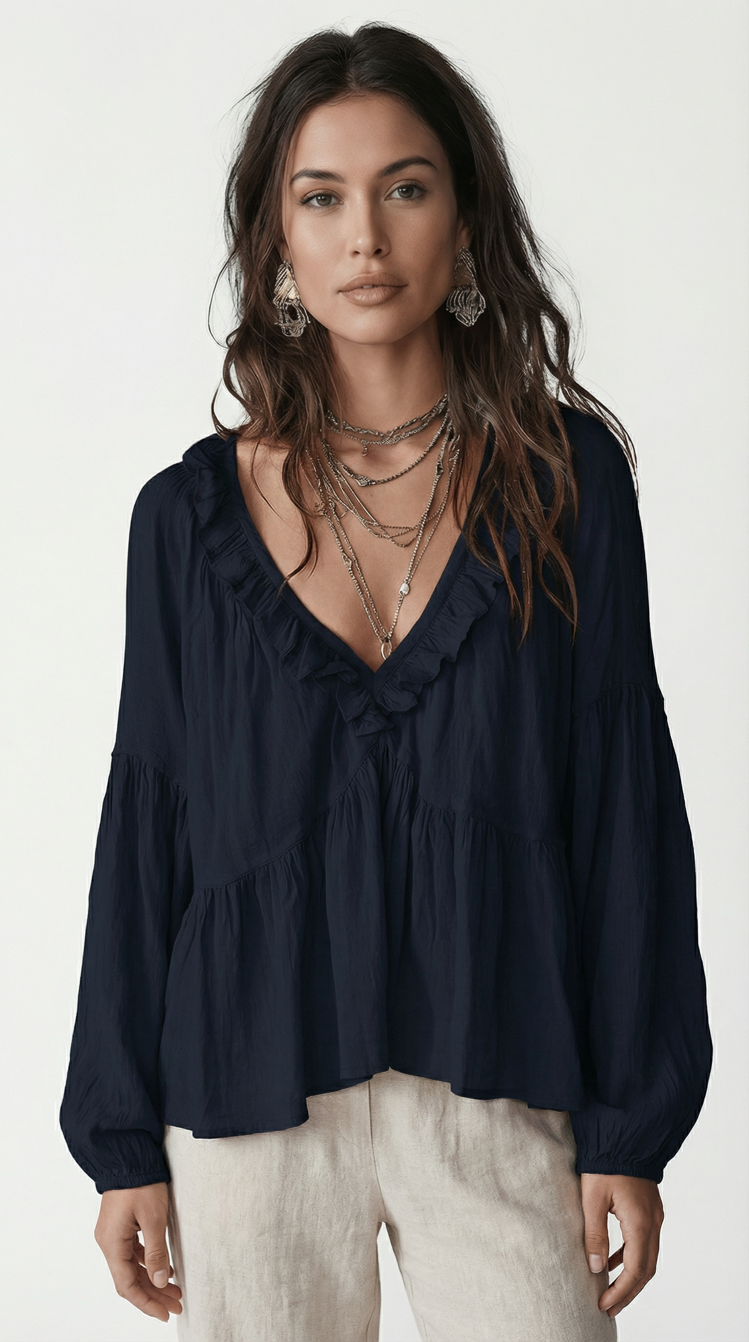 Woman wearing a dark blue blouse with ruffled details on a white background