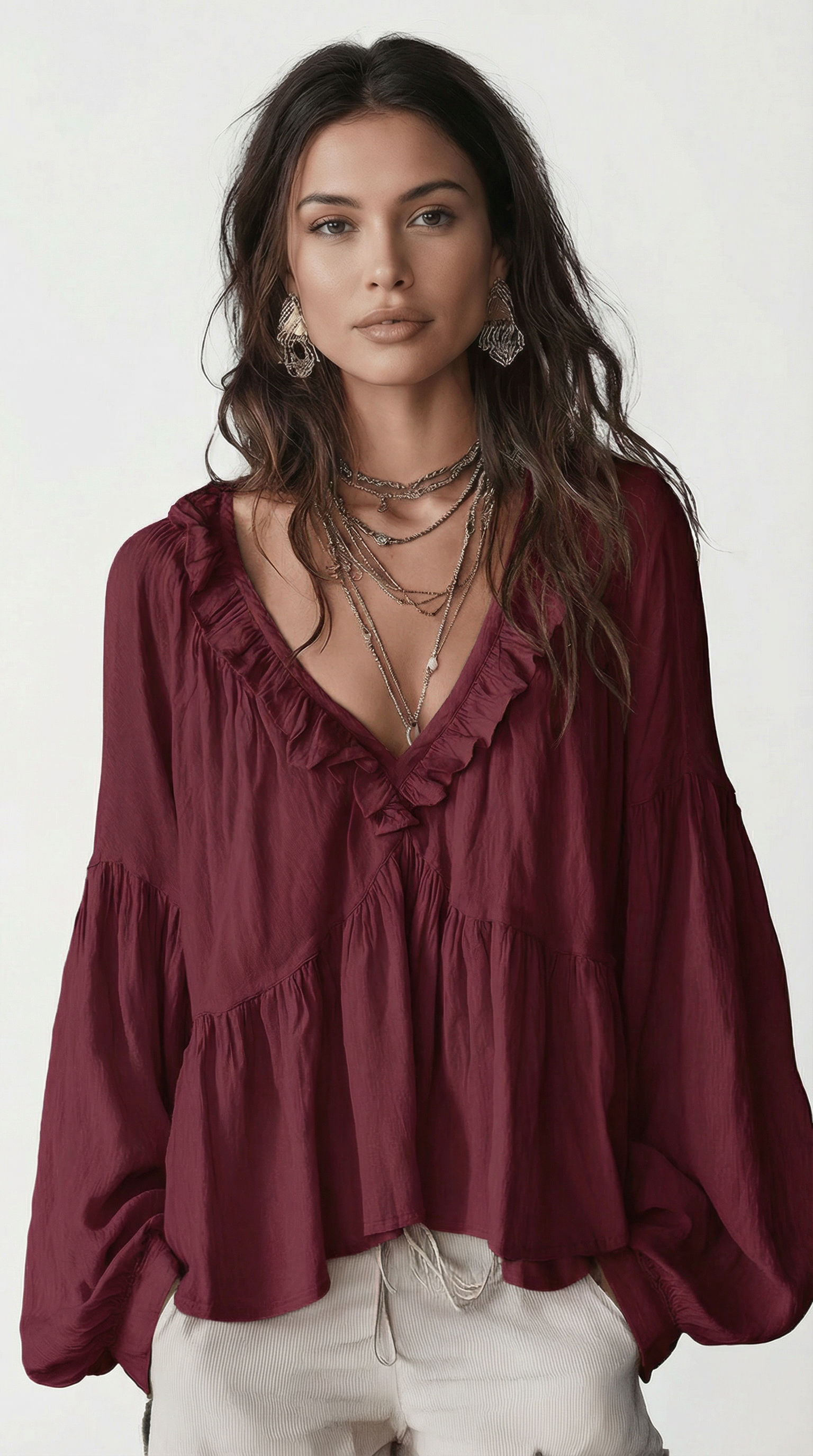 Woman wearing a burgundy blouse with ruffled details on a white background