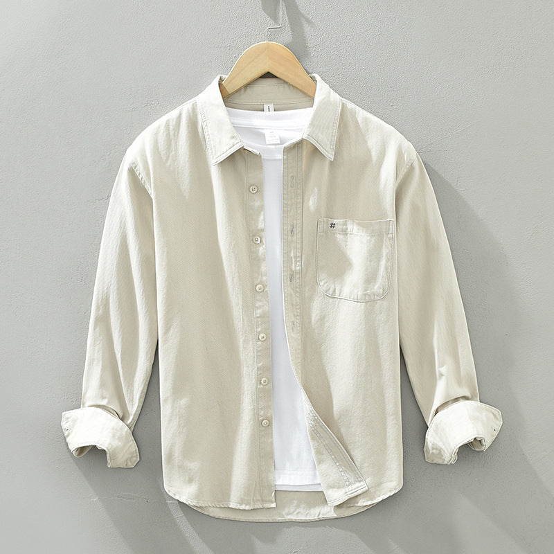 Beige button-up shirt on a hanger against a gray background