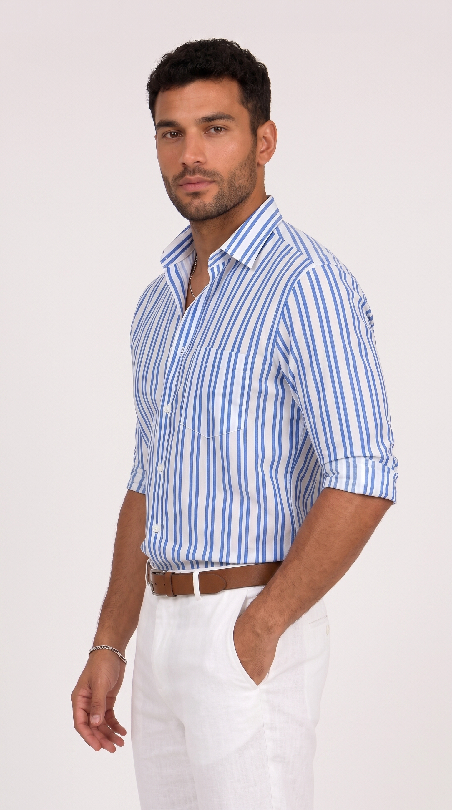 A man wearing a blue and white vertically striped button-down shirt with white trousers and a brown belt, standing against a plain light background, from Meleche Fashion USA or Meléche (short as (Mé))